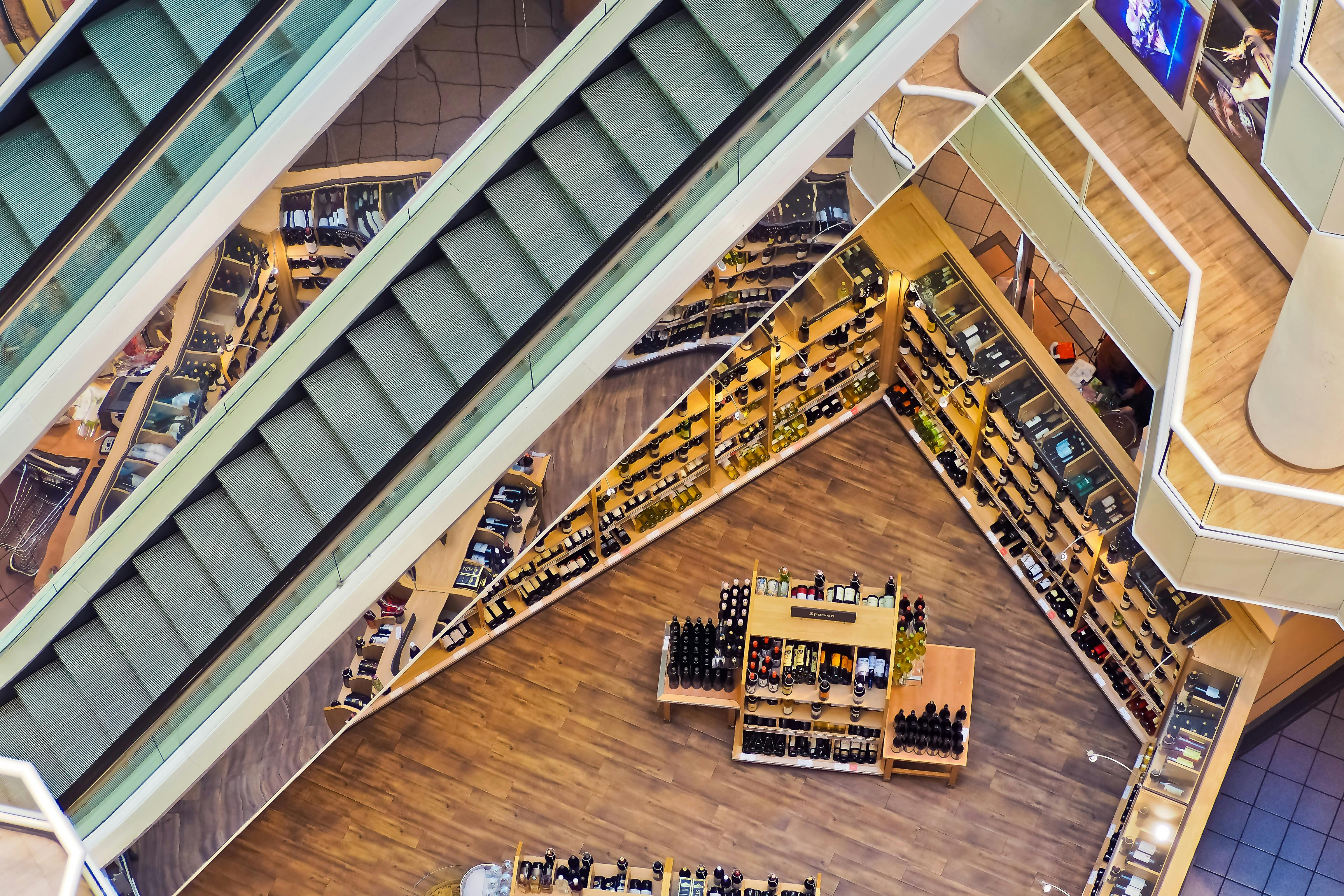 Aerial view of modern multi-level retail space with escalators and organized product displays, representing structured business growth, clear operational pathways, and systematic organizational design