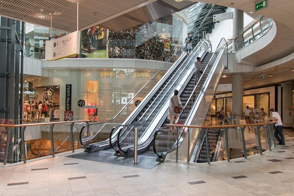 Empty retail kiosk space in modern shopping center with bright lighting and foot traffic, representing available temporary retail opportunities